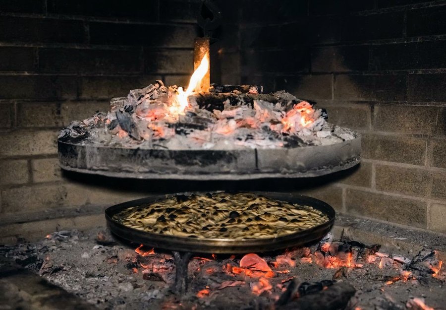 Traditional wood-fired stone oven baking fresh local bread and authentic dishes at Ura e Kovaçit
